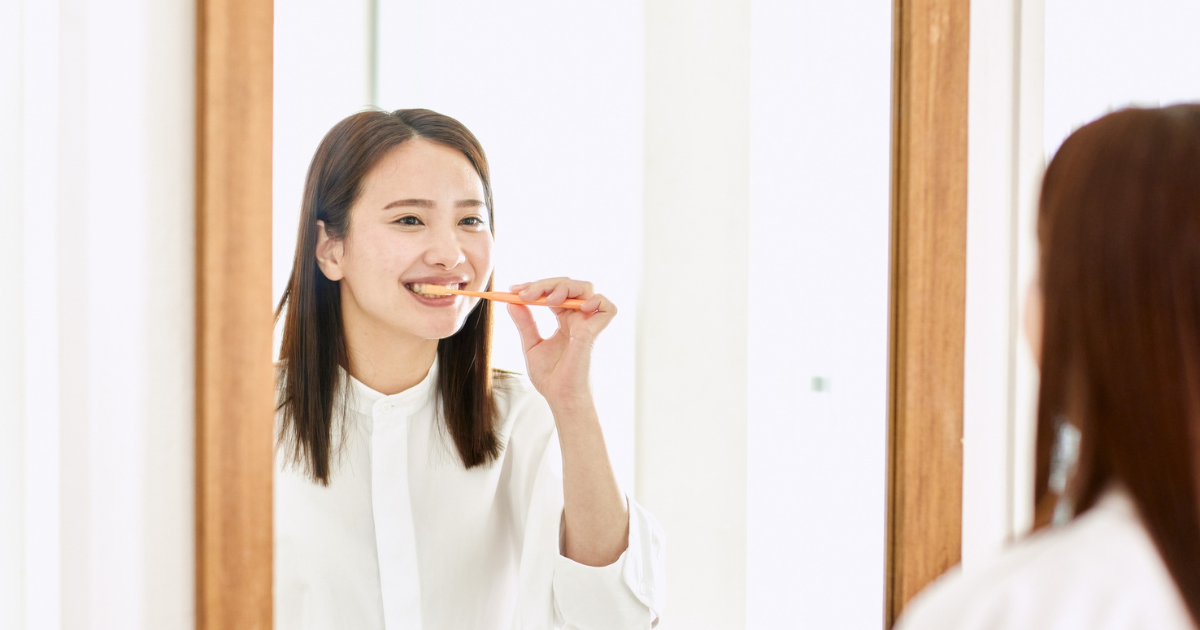 person brushing teeth noticing bleeding gums in mirror