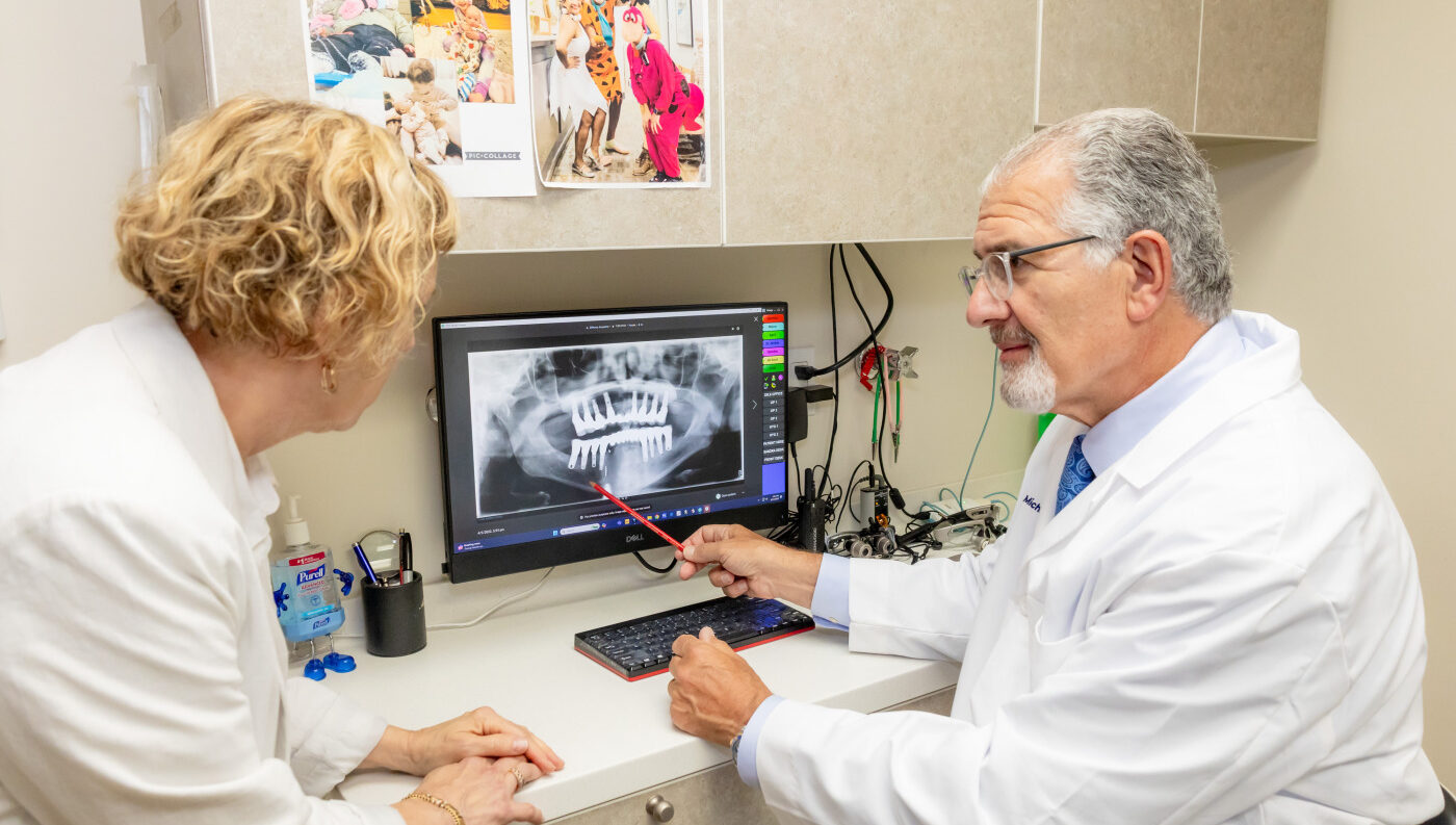 Dentist reviewing dental X-rays with a patient while discussing alternatives to dentures in a New York City dental office.