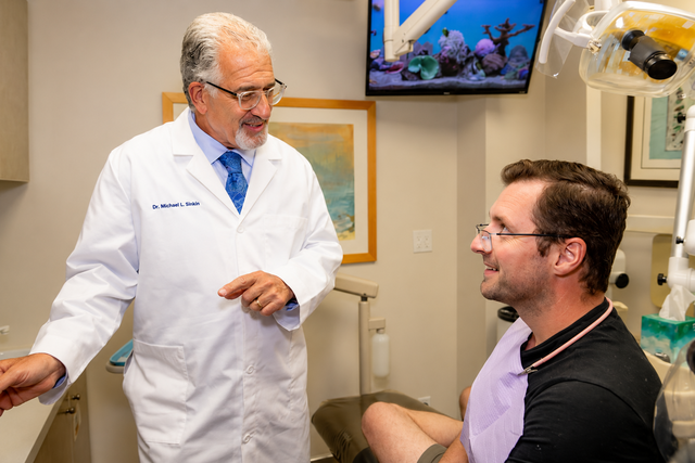 Patient relaxed in dental chair discussing a crowned tooth with her Midtown Manhattan dentist